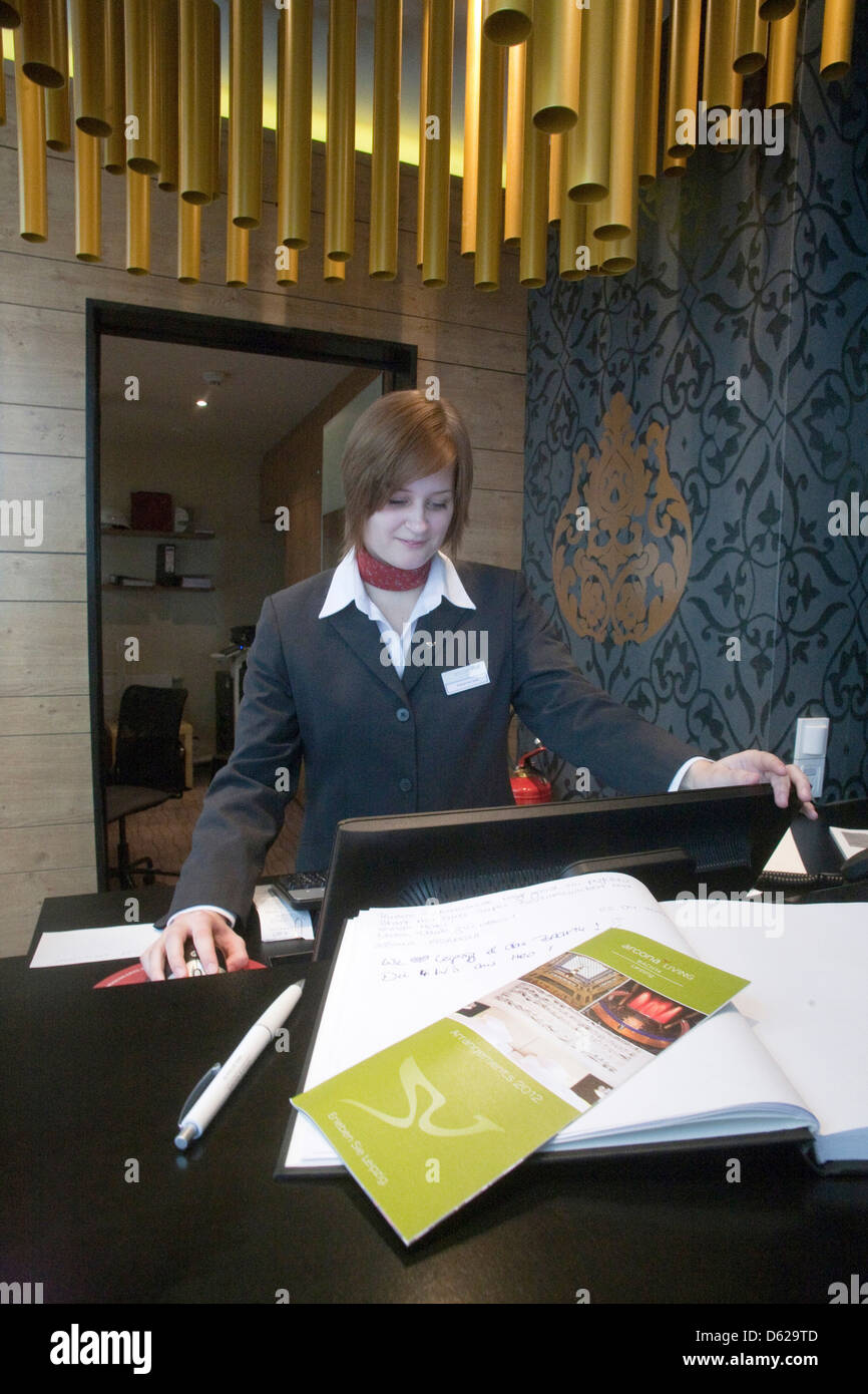 Germania a Leipzig. Personale di front desk attendant a Arcona Living hotel direttamente attraversata la strada da San Tommaso Chiesa. Foto Stock