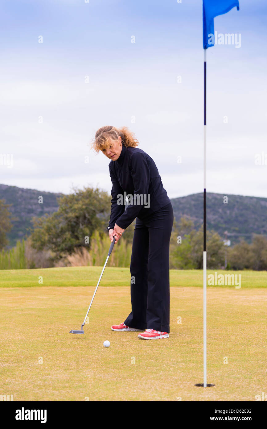 Di mezza età Caucasian donna di 45 anni utilizzando il putter su un golf green Foto Stock