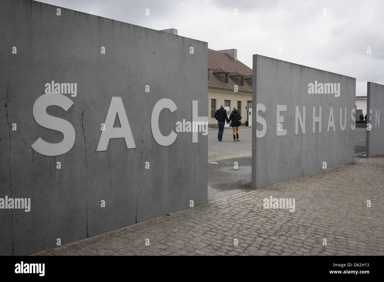 Un turista giovane immettere il Sachsenhausen Memorial e Museo. Sachsenhausen è stato un nazista e sovietica del campo di concentramento di Oranienburg, 35 chilometri (22 miglia) a nord di Berlino, Germania, utilizzato principalmente per i prigionieri politici dal 1936 alla fine del terzo Reich nel maggio 1945. (Più didascalia nella descrizione). Foto Stock