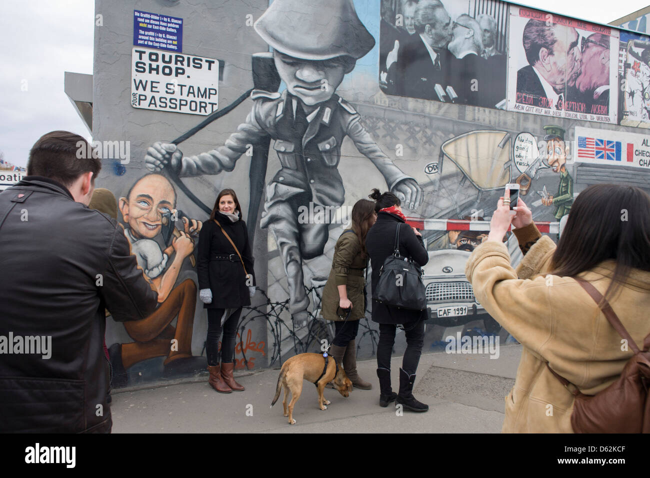 Gli ospiti godono di arte sul vecchio Muro di Berlino presso la East Side Gallery, l'ex confine comunista tra Berlino Ovest e Berlino Est durante la Guerra Fredda. Il muro di Berlino è stata una barriera costruita dalla Repubblica democratica tedesca, la Germania Est) a partire dal 13 agosto 1961, che completamente tagliata (via terra) a Berlino Ovest dal circostante della Germania orientale e di Berlino Est. .. (Di più nella descrizione). Foto Stock