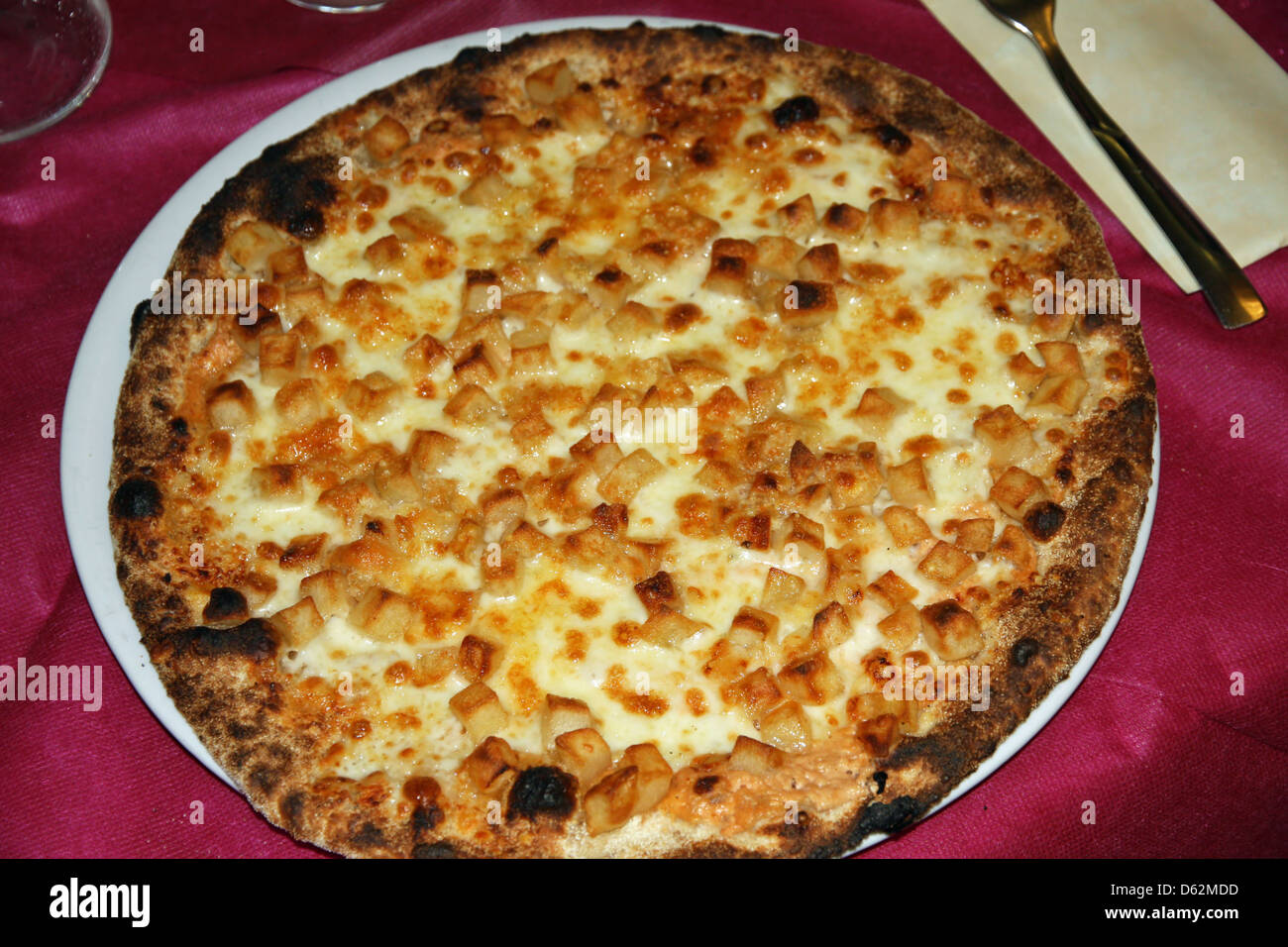 Una gustosa pizza cotta con forno a legna con formaggio e pezzi di patate Foto Stock