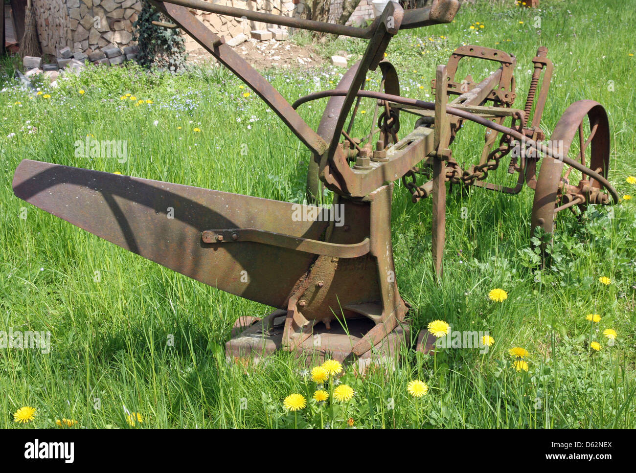 Vecchio arrugginito aratro per lavorare la terra in Prato verde Foto Stock