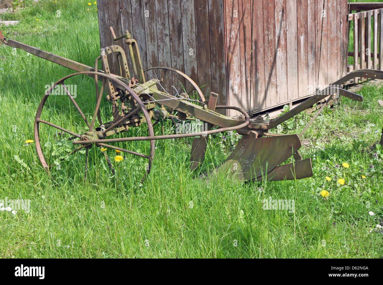 Vecchio arrugginito aratro per lavorare la terra in Prato verde Foto Stock