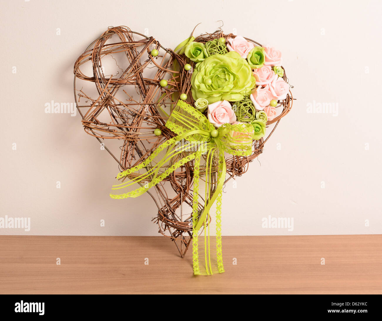 Decorazione di interni, decorativo cuore di vimini con viola e verde rose. Foto Stock