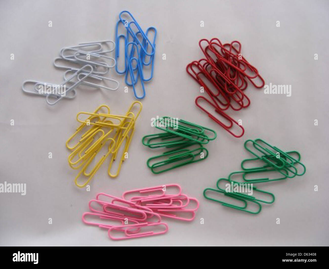 Una raccolta di graffette multicolore disposte in modo ordinato. Le graffette sono materiali di consumo comuni per ufficio utilizzati per organizzare documenti e documenti. Foto Stock