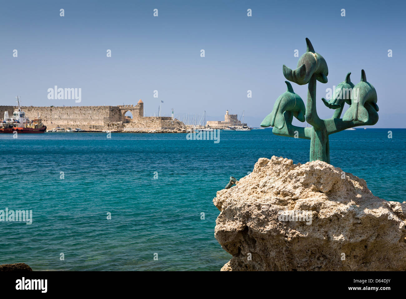 Le Statue dei delfini e il vecchio castello e il faro sul porto di Mandraki sull' isola di Rodi, Grecia. Foto Stock