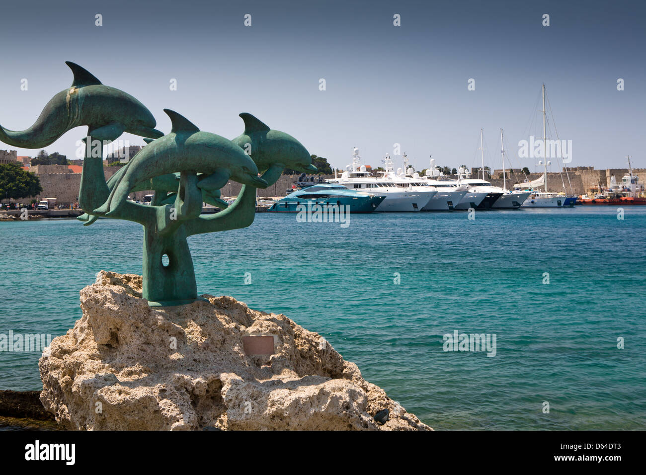 Dolphin statue e yacht ormeggiati in porto Mandraki sull' isola di Rodi, Grecia. Foto Stock