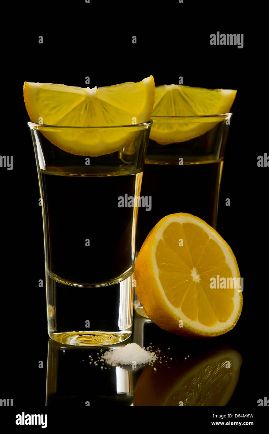 Due colpi di tequila con limone e sale su uno sfondo nero Foto Stock