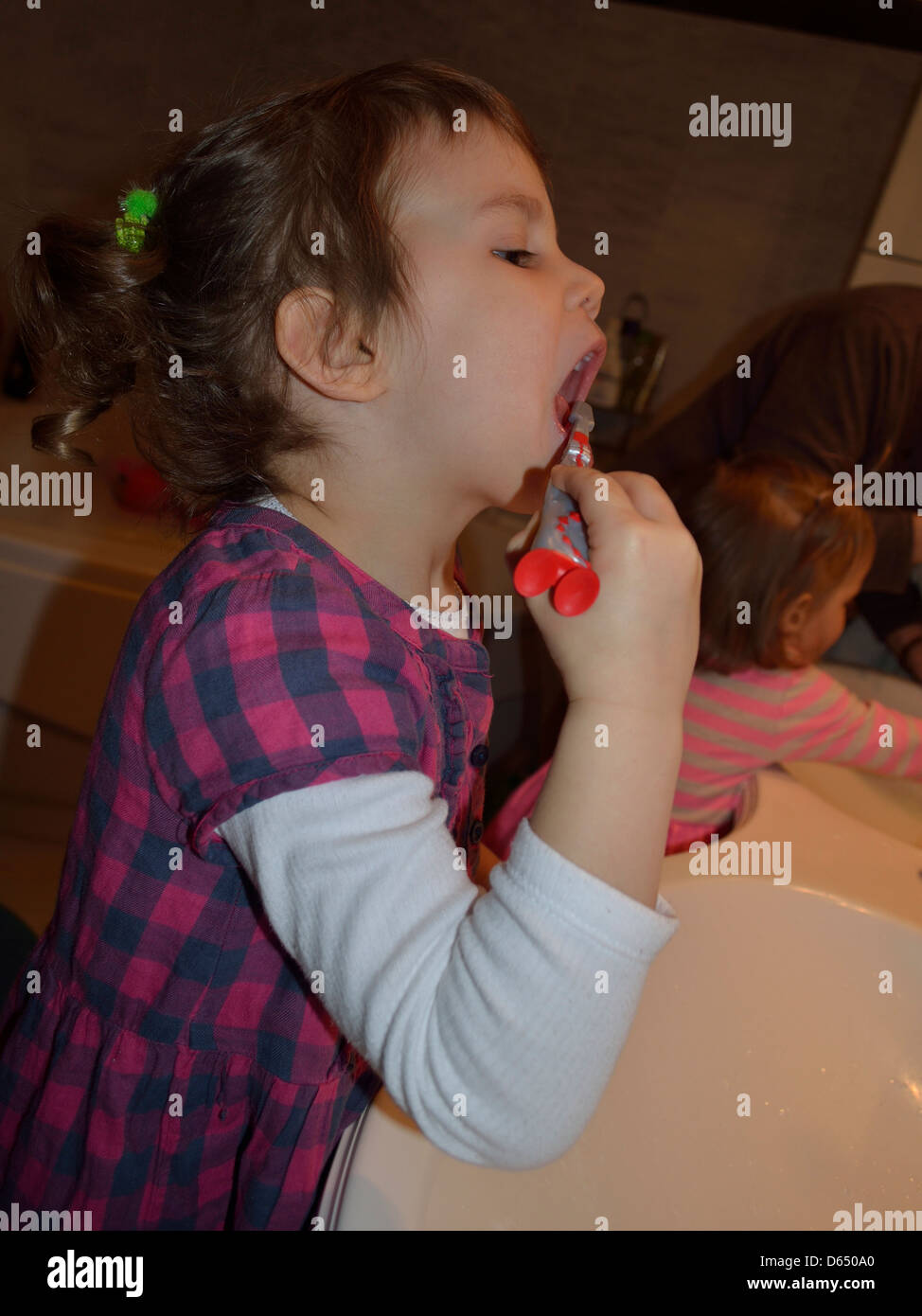 Bambina di spazzolare i denti al lavandino Foto Stock