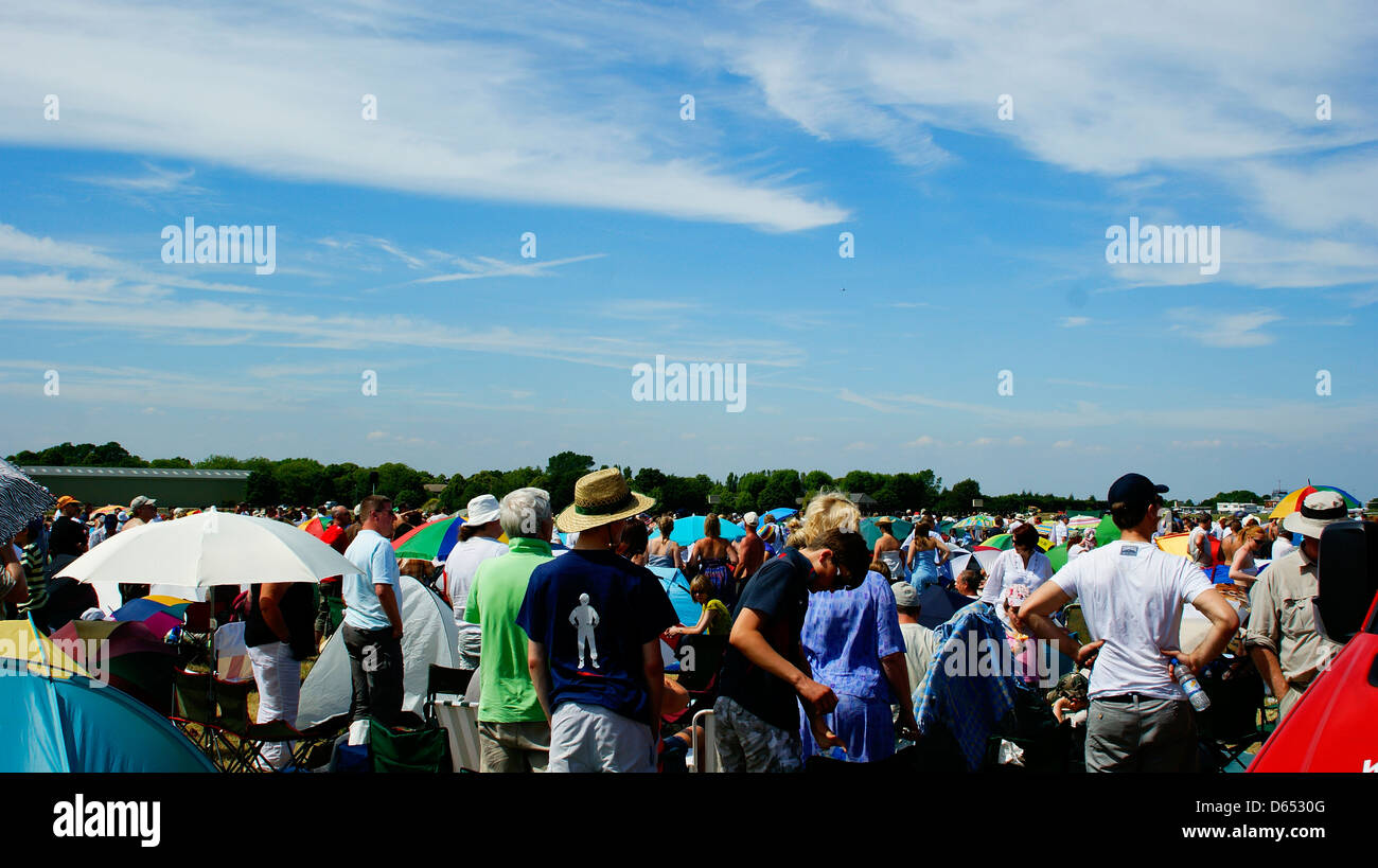 La folla di persone ombrelloni top cappelli nuvole uk meteo Foto Stock