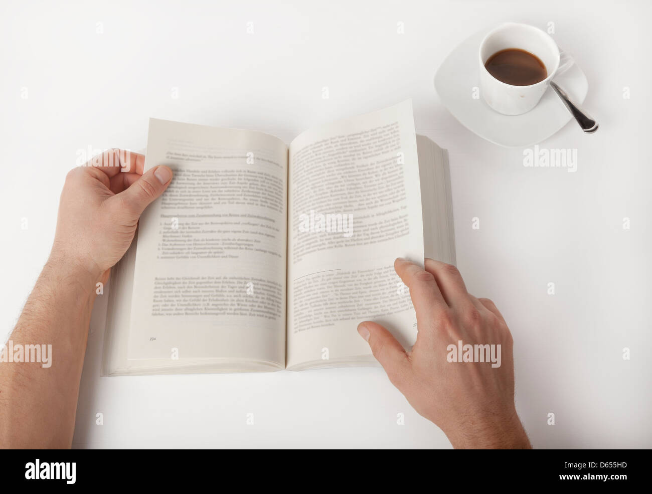 Un maschio di studente la lettura di un libro, con una tazza di caffè Foto Stock