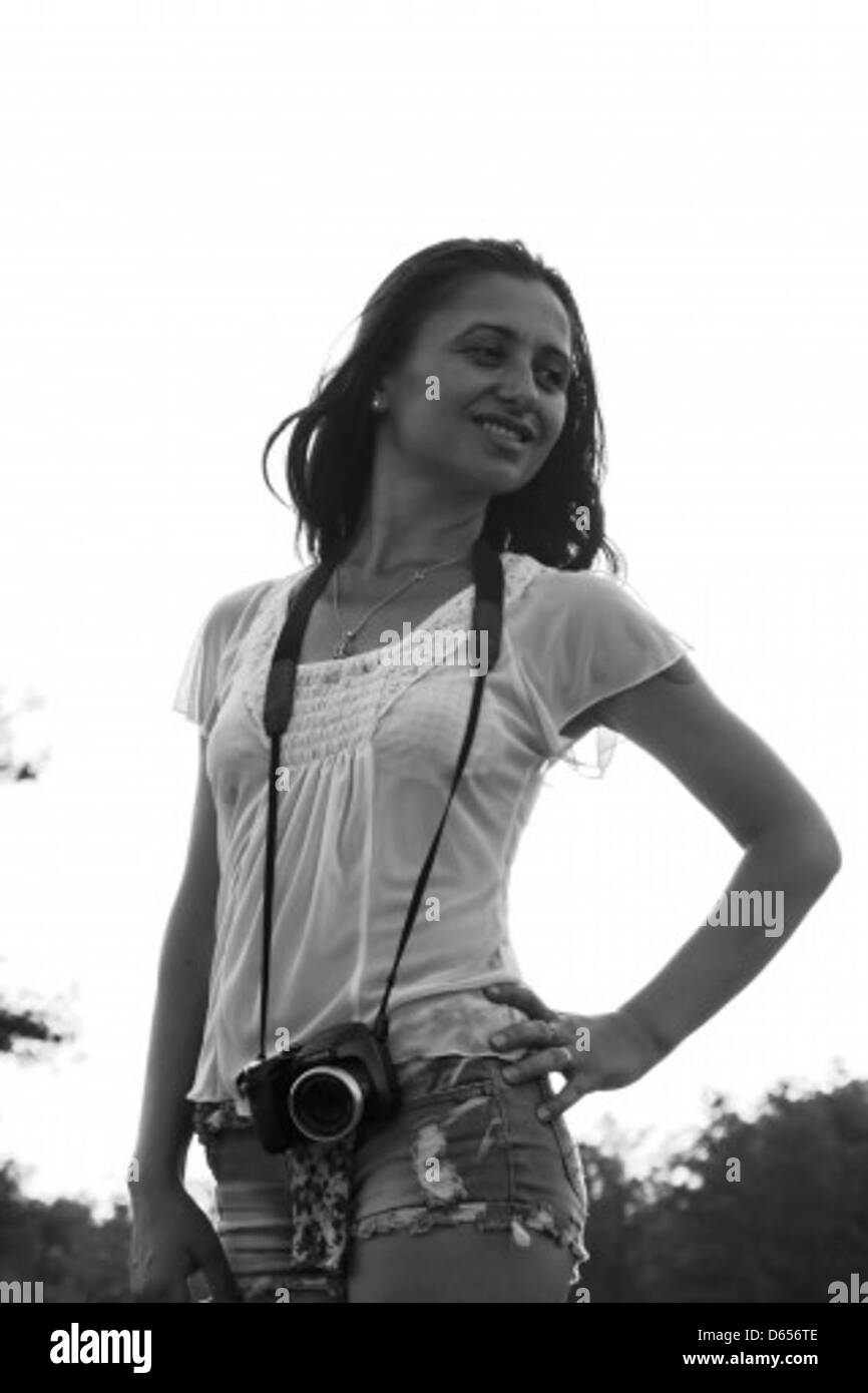 Questa immagine mostra una giovane donna che ama la natura in un ambiente estivo soleggiato. Sorride e immersa nell'ambiente naturale, circondata dal verde e dalla luce solare. Foto Stock