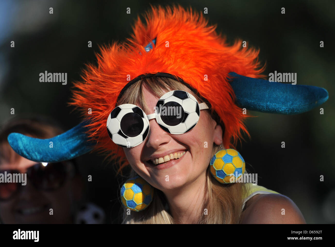 Una donna con un cappello olandese e ucraino anelli auricolari si siede su una panchina di fronte allo stadio prima della UEFA EURO 2012 GRUPPO B partita di calcio nei Paesi Bassi vs Germania al Metalist Stadium di Kharkiv, Ucraina, 13 giugno 2012. Foto: Andreas Gebert dpa Foto Stock