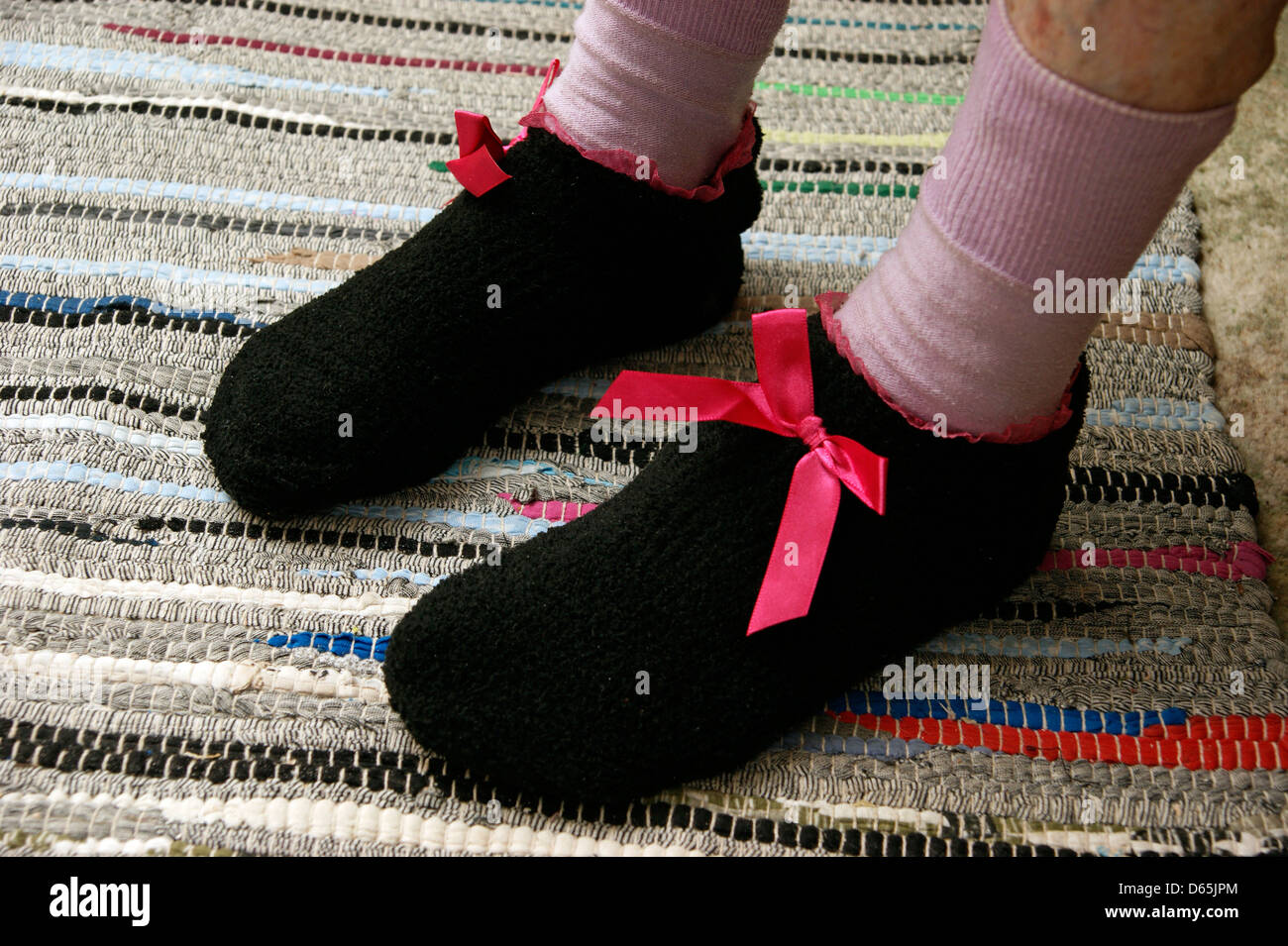 Donna anziana di indossare i calzini e pantofole in maglia per mantenere caldo e accogliente in inverno Foto Stock