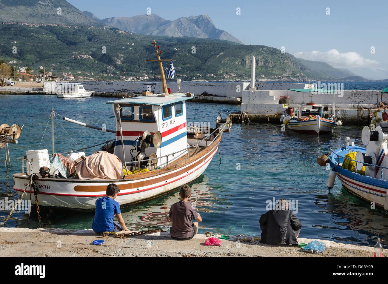 I bambini la pesca nel porto nel piccolo villaggio di pescatori di Ayios Nikolaos, nella parte esterna di Mani, sud del Peloponneso, della Grecia. Foto Stock
