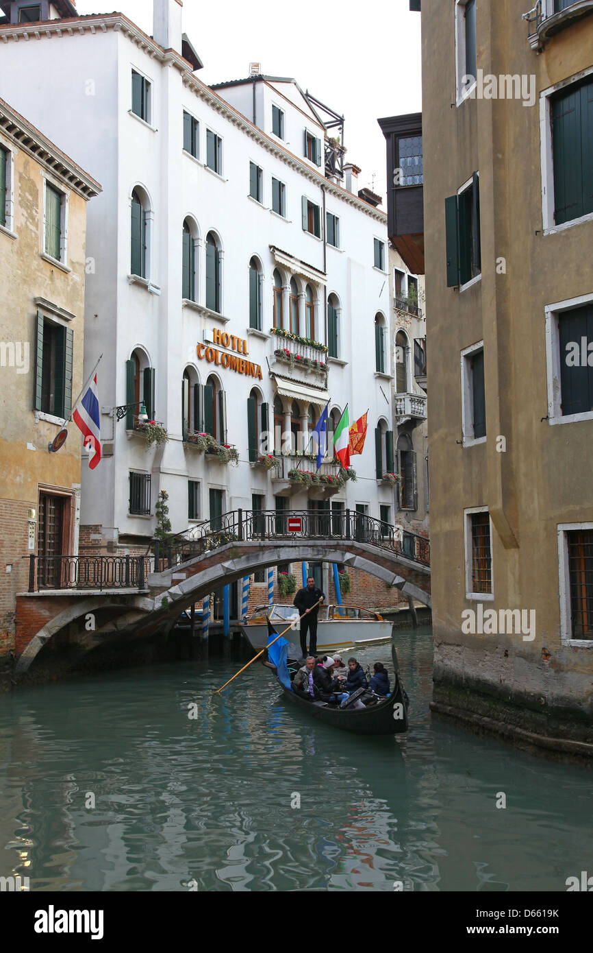 Un gondoliere e la sua gondola su un piccolo canale laterale con il colorato di vecchi edifici dell'Hotel Colombina a Venezia Italia Foto Stock