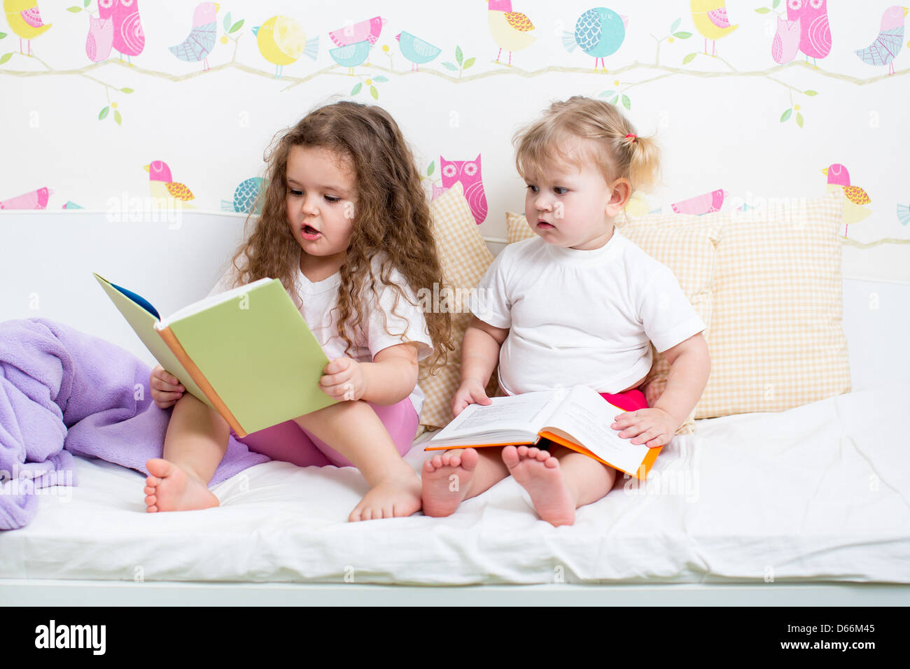 I ragazzi sorelle la lettura di un libro a letto Foto Stock