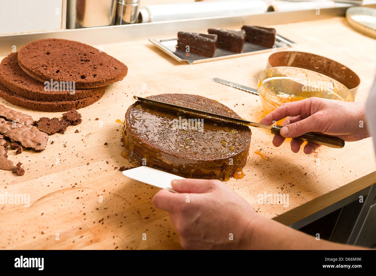 Cuocere la salsa di diffusione sulla superficie della torta con un coltello in cucina Foto Stock