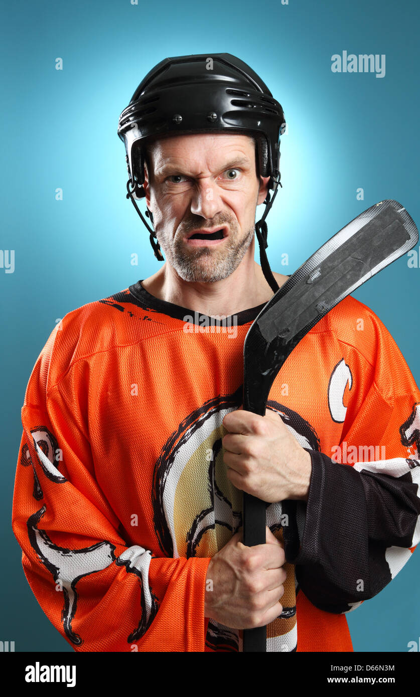 Divertente colpo di un giocatore di hockey appoggiata sulla sua mazza da hockey rendendo un arrabbiato espressione. Foto Stock