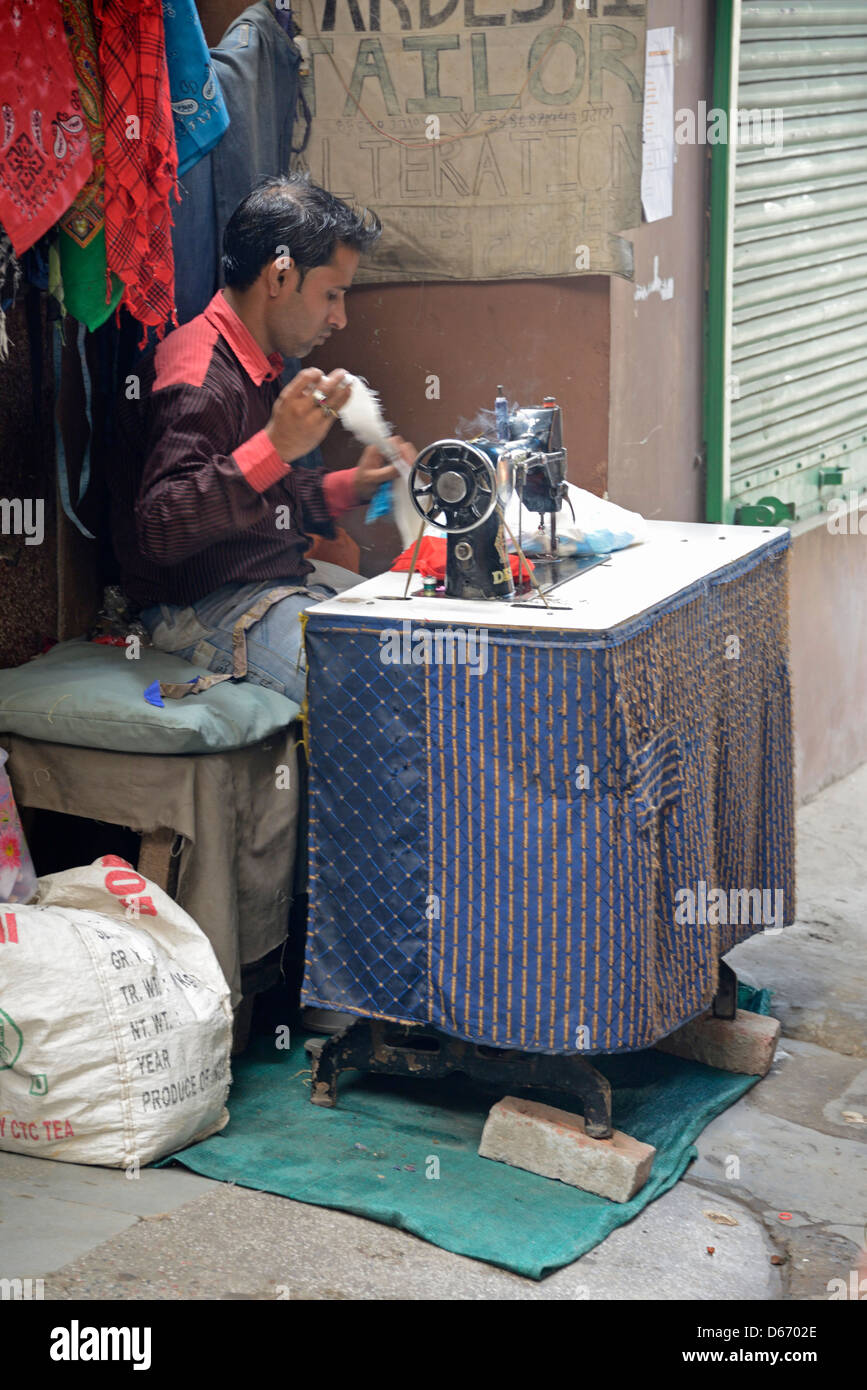 Un tibetano occupato cucire sulla sua macchina da cucire in un passaggio stretto nel Majnu Ka Tila campo profughi tibetano in Delhi, India Foto Stock