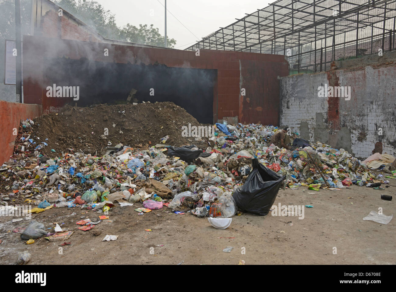 Masterizzazione di un mucchio di rifiuti di strada in una delle baraccopoli di Vecchia Delhi in India Foto Stock