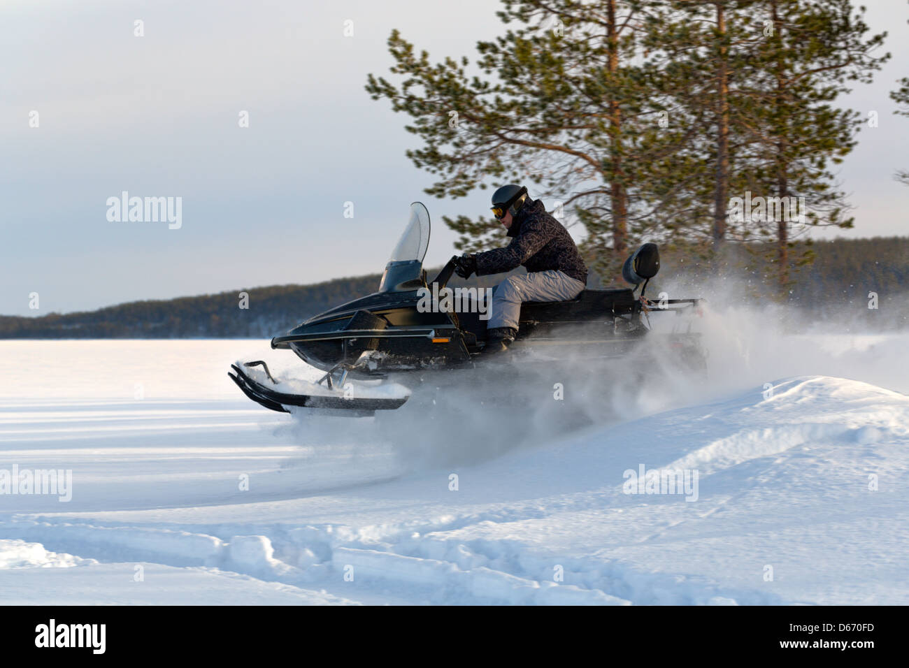 Uomo in sella ad una motoslitta sul lago Foto Stock