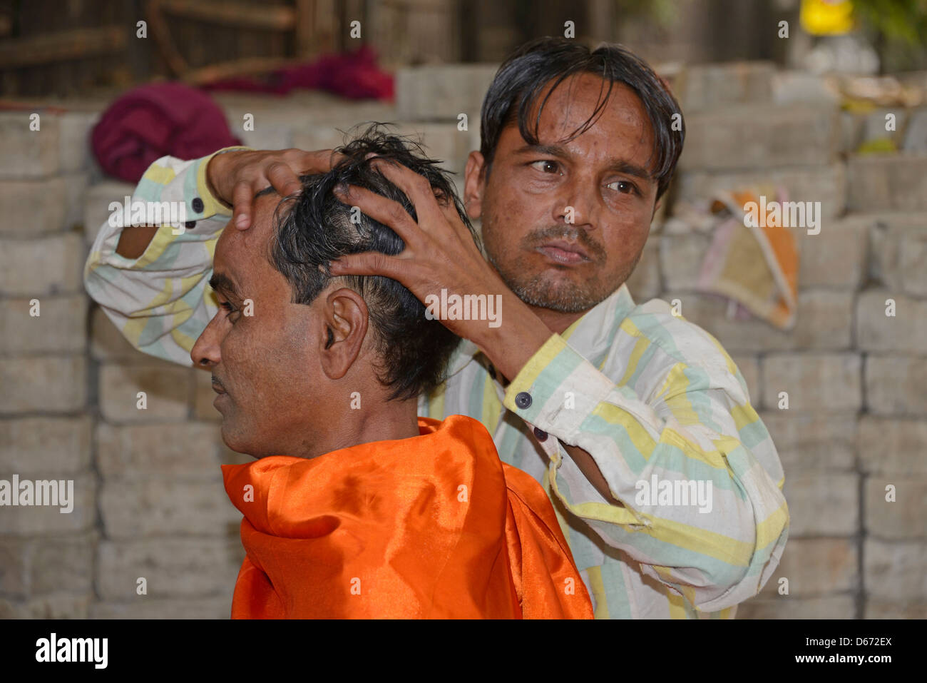 Un barbiere che dà al suo cliente un massaggio della testa su un marciapiede di strada in Janpath Lane, Nuova Delhi, India. Foto Stock