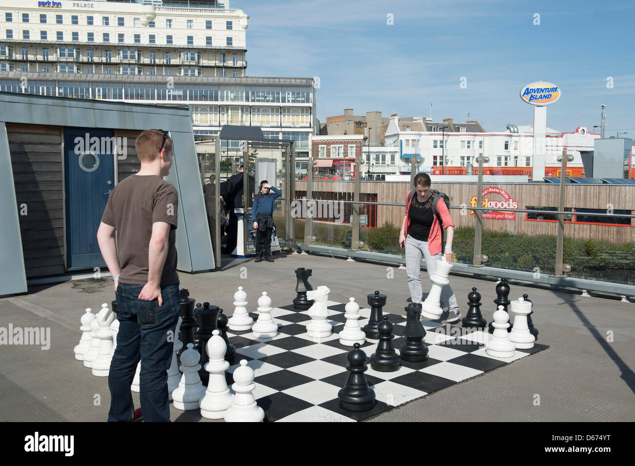 Una giovane coppia godere del bel tempo in cui giocare un gioco di dimensioni oltre a giocare a scacchi all'inizio del molo di Southend, in Essex, UK. Foto Stock