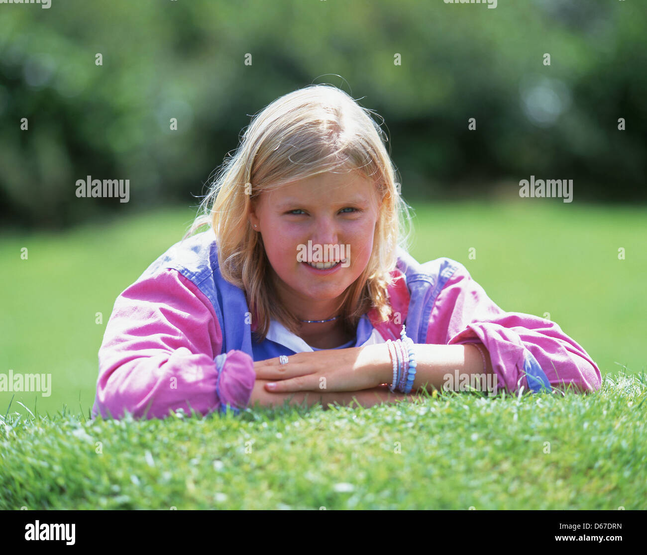 I giovani adolescenti ragazza bionda giacente sulla banca di erba, Winkfield, Berkshire, Inghilterra, Regno Unito Foto Stock