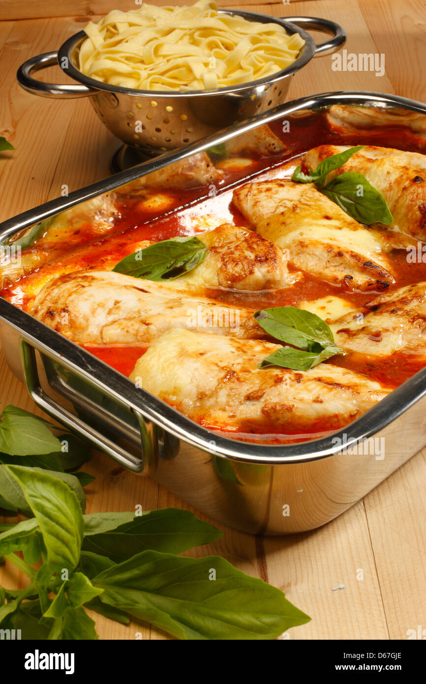 Il pollo al forno con salsa di pomodoro e basilico in una teglia da forno e tagliatelle in un argento sgocciolatoio Foto Stock
