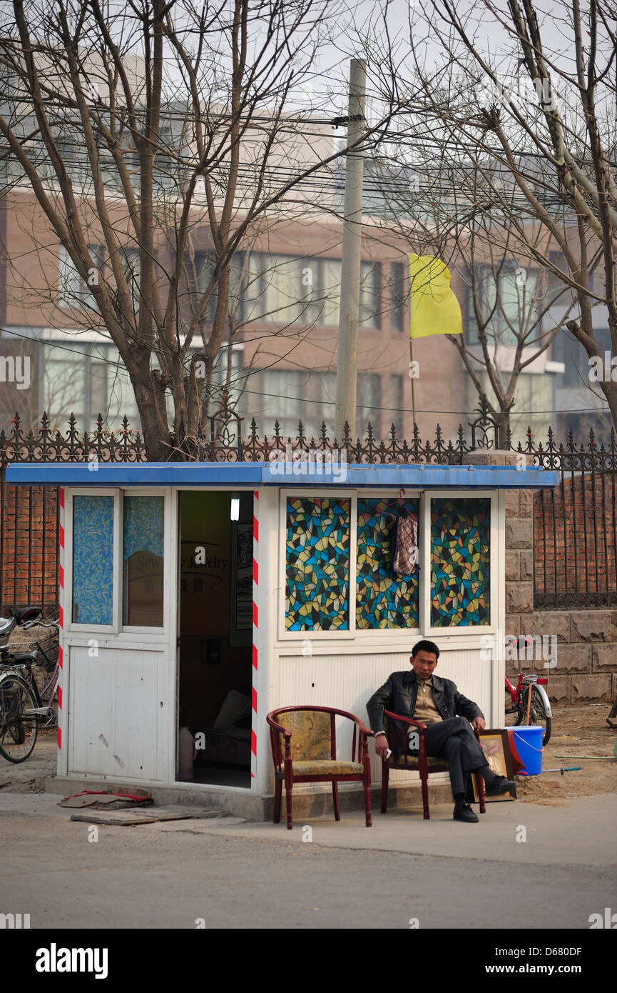 Pechino, Cina - 3 Aprile:un uomo si siede al di fuori della fabbrica di cabina di sicurezza nel sobborgo occidentale di Pechino il 3 aprile 2013. Foto Stock