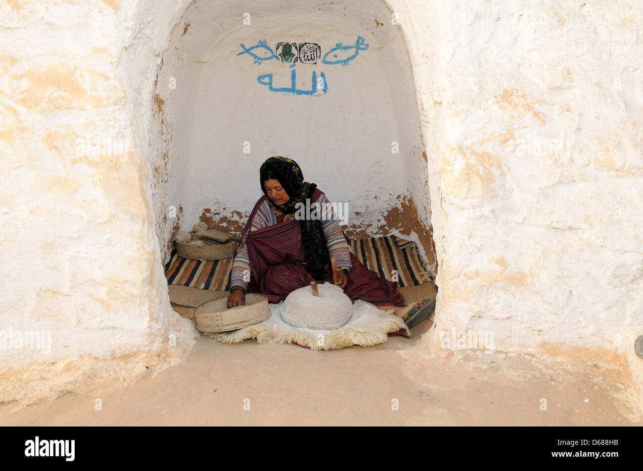 Berber donna granella di fresatura nella sua grotta troglodita Matmara casa Tunisia Foto Stock
