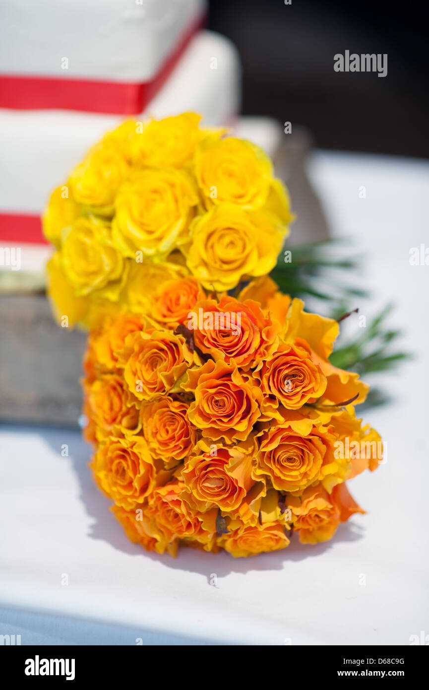 Bouquet nozze di arancione e giallo rose da una torta Foto Stock
