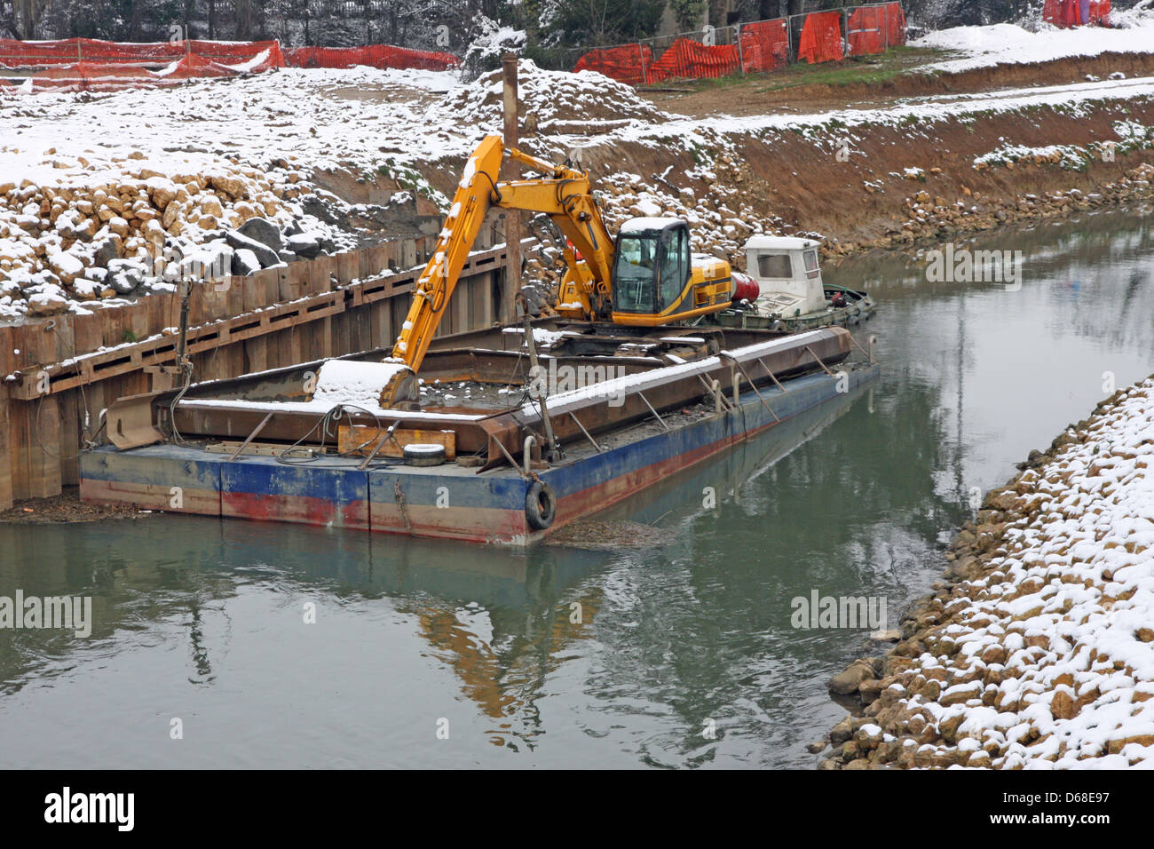 Escavatore bulldozer in una chiatta durante il lavoro del fiume in inverno Foto Stock