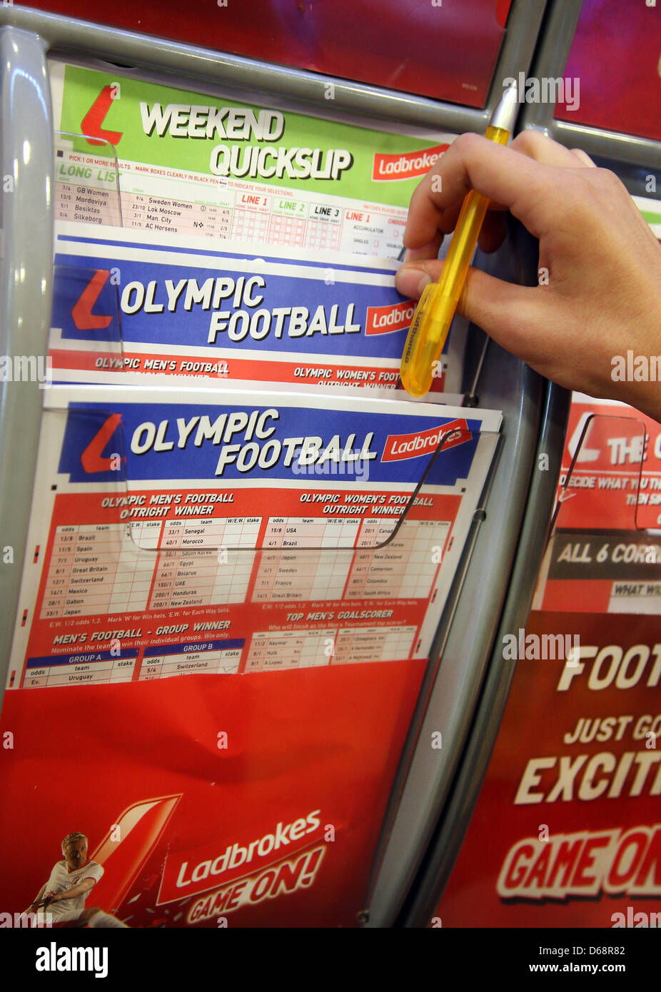 Illustrazione - un client tira di biglietti di scommesse al di fuori di un ripiano interno il contatore di un'agenzia di scommesse a Londra, in Gran Bretagna, 20 luglio 2012. Il London 2012 Giochi Olimpici avranno inizio il 27 luglio 2012. Foto: Friso Gentsch dpa Foto Stock