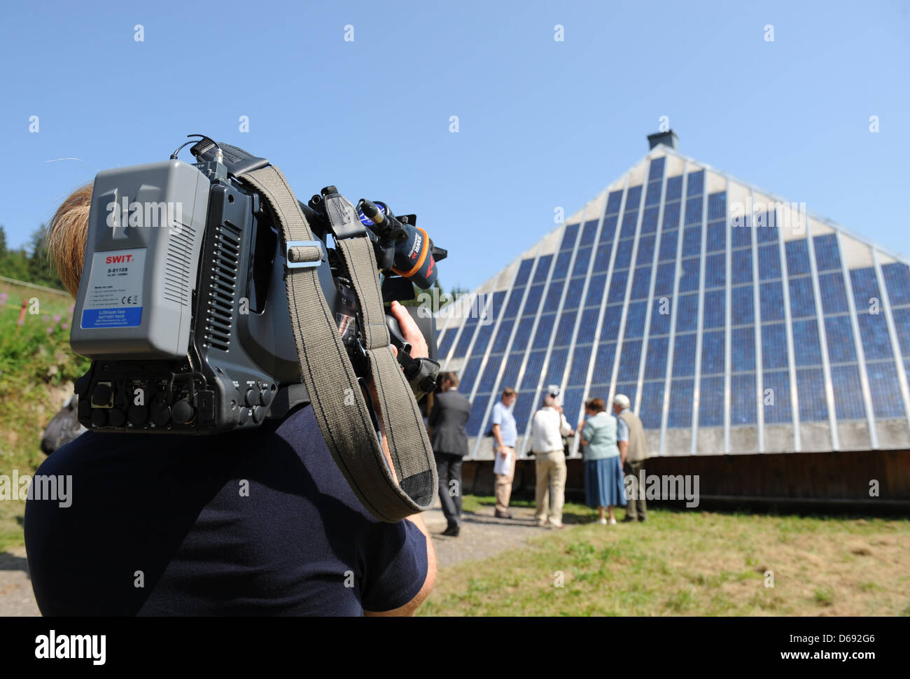 Un cameraman films i pannelli solari sul tetto della locanda Rappendecker Huette in Oberried, Germania, 27 luglio 2012. Rappendecker Huette fu il primo solare-poweered inn in Europa. È stato un progetto di ricerca dell'Istituto Fraunhofer fin dal 1987 ed è considerato essere una vetrina modello della svolta energetica. L'inn riceve un'altra cella a combustibile. Foto: Patrick Seeger Foto Stock