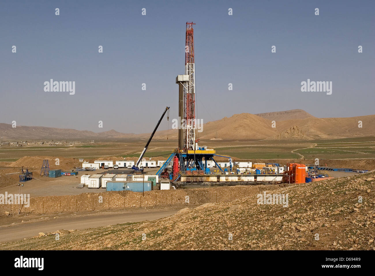 Olio e gas esplorazione onshore rig sito nella valle con montagne all orizzonte. Il Kurdistan iracheno, Iraq settentrionale Foto Stock