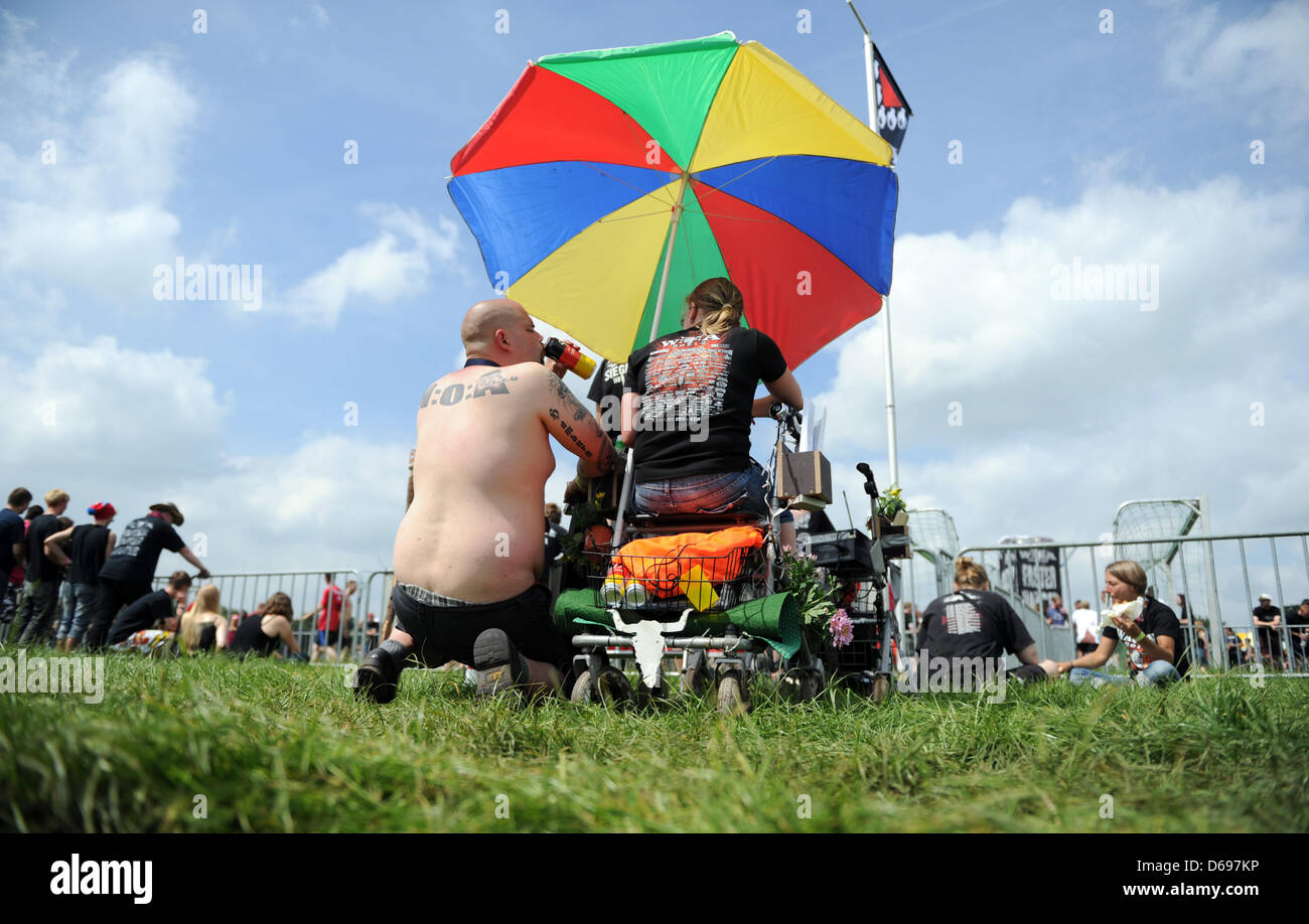 Visitatori sedersi sotto un ombrello e su un rollator sui motivi del Wacken  Open Air Festival in Wacken, Germania, 01 agosto 2012. Il più grande del  mondo di musica heavy metal festival