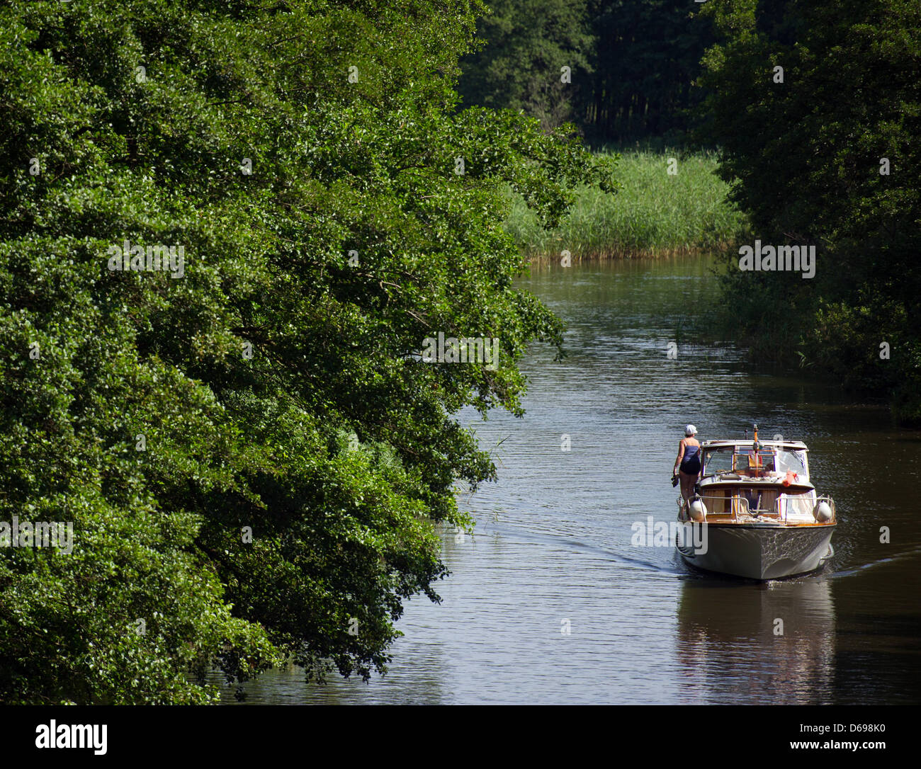 Un dilettante capitani manzi la sua barca lungo un canale a Templin, Germania, 01 agosto 2012. Il parco di natura Uckermaerkische visto (Uckermark Laghi) nonché il Feldberger Seenlandschaft (Feldberg Lake District) possono essere entrambi raggiunti da Berlino attraverso il Havel e sono un paradiso per gli appassionati di capitani. Brandeburgo ha oltre 3.000 laghi e 30.000 km di acqua fluente, 1.600 km di cui possono essere utilizzati Foto Stock