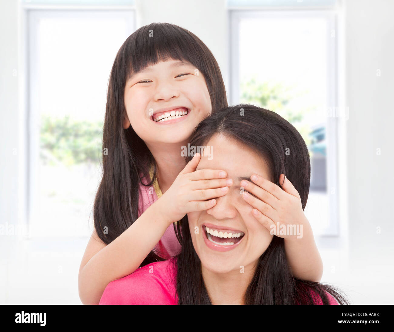 Felice bambina coprire la sua madre gli occhi per il divertimento Foto Stock