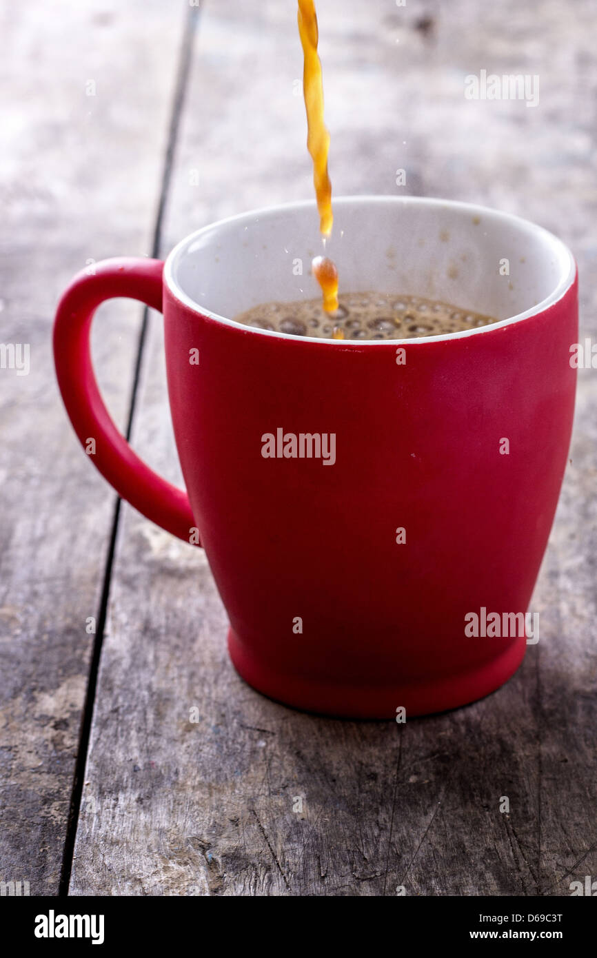 Versando una nuova tazza di caffè appena preparato contro lo sfondo di legno. Studio shot. Foto Stock