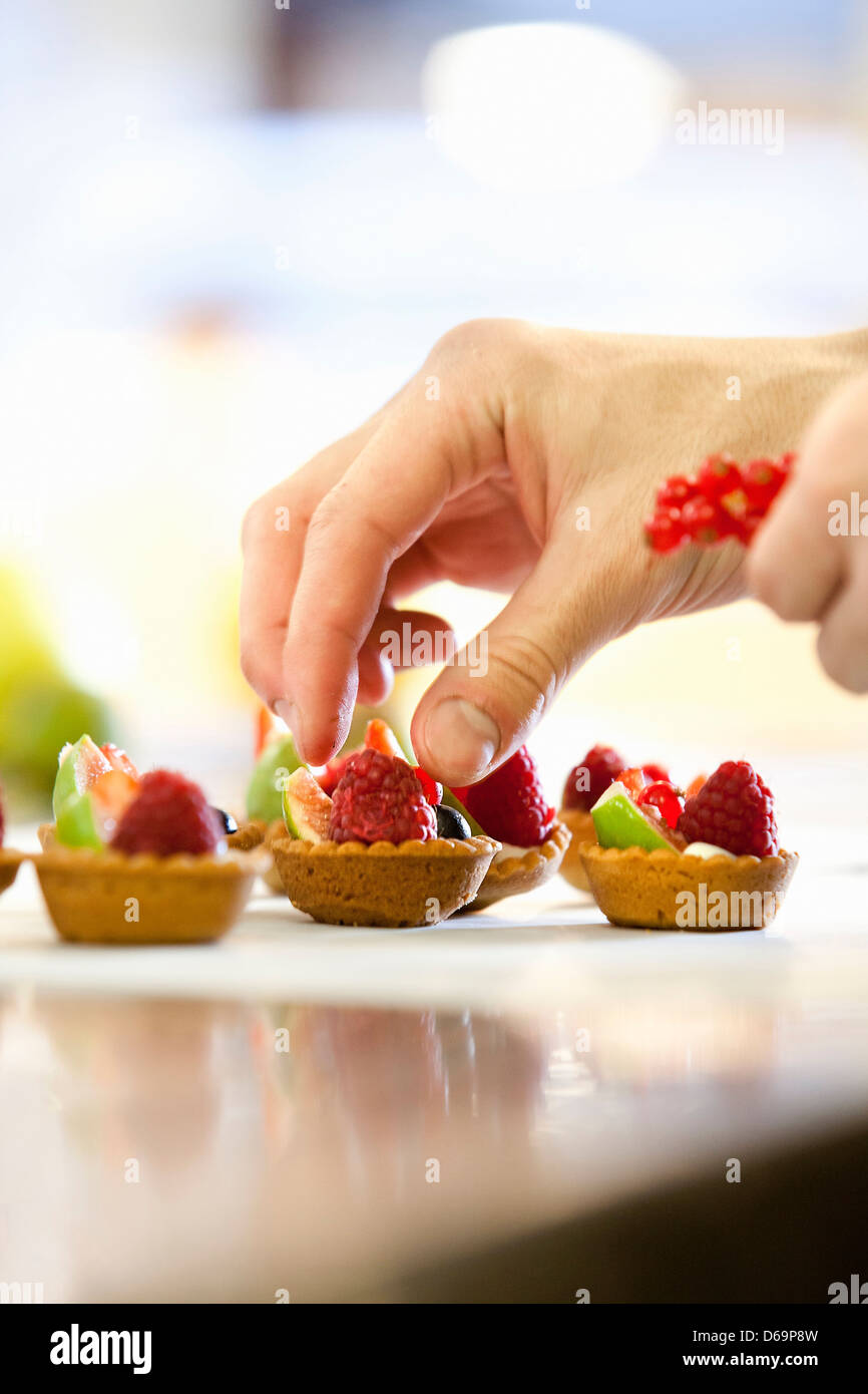 Baker rendendo crostate di frutta in cucina Foto Stock