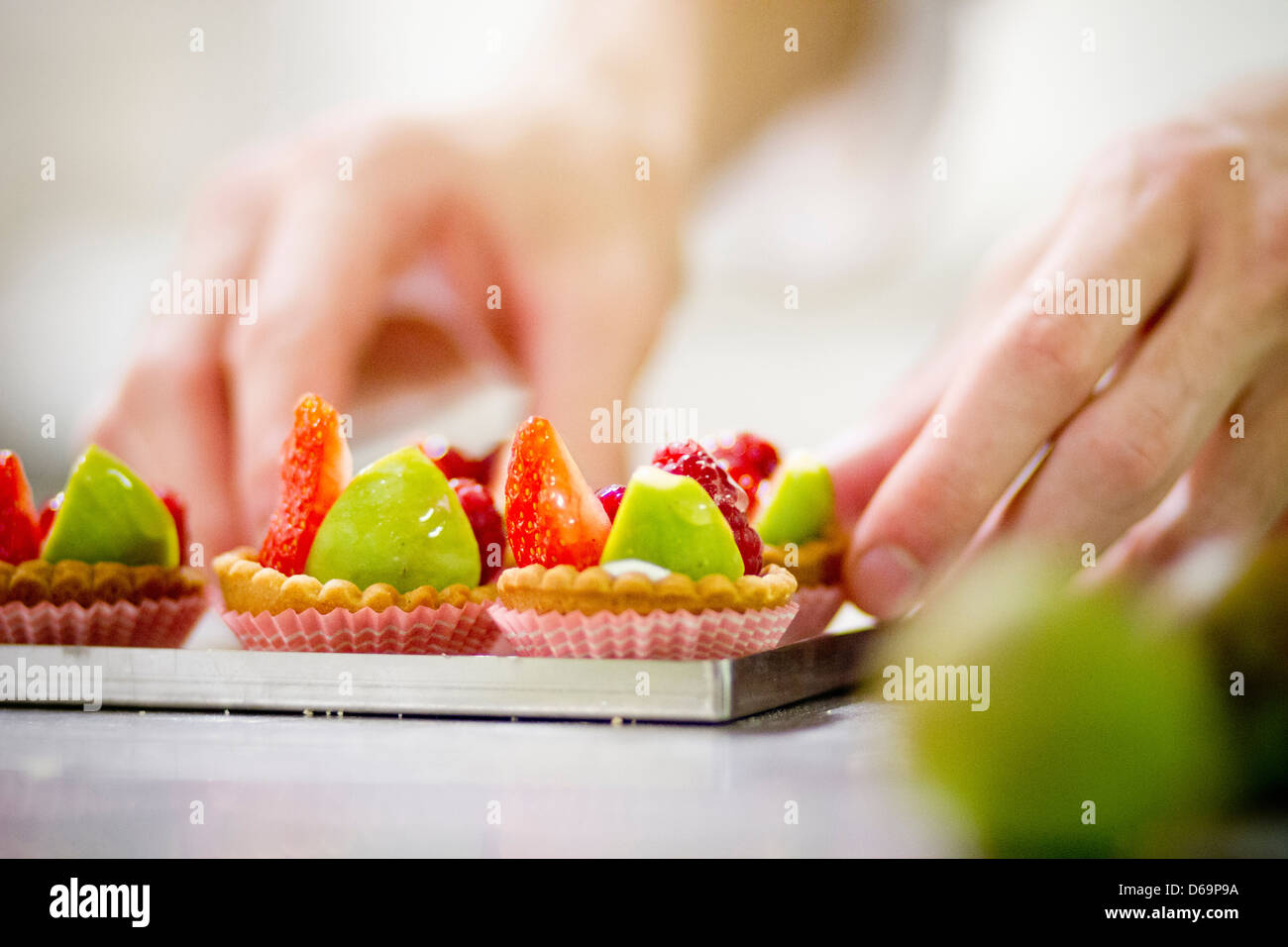 Baker rendendo crostate di frutta in cucina Foto Stock
