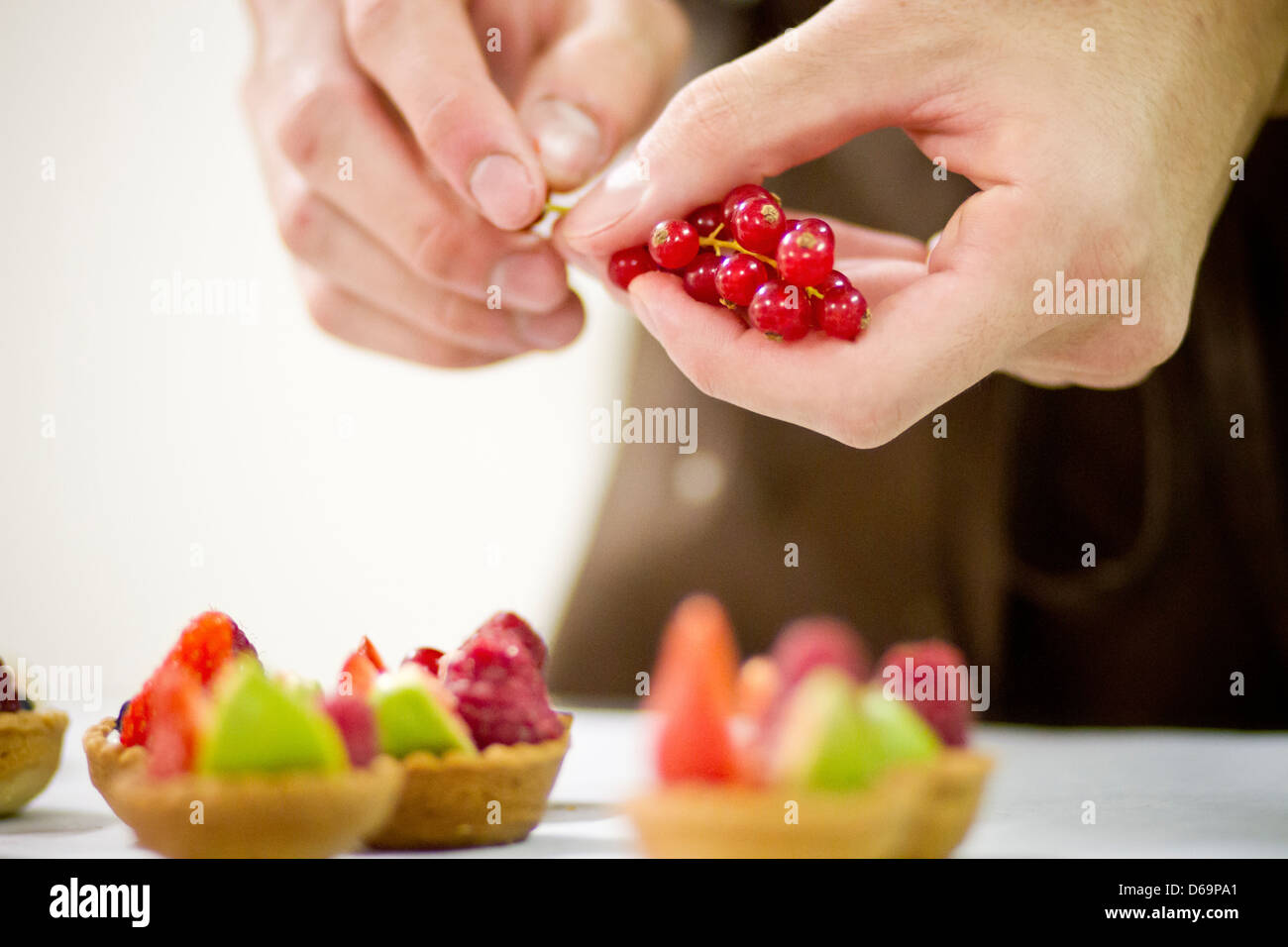Baker rendendo crostate di frutta in cucina Foto Stock