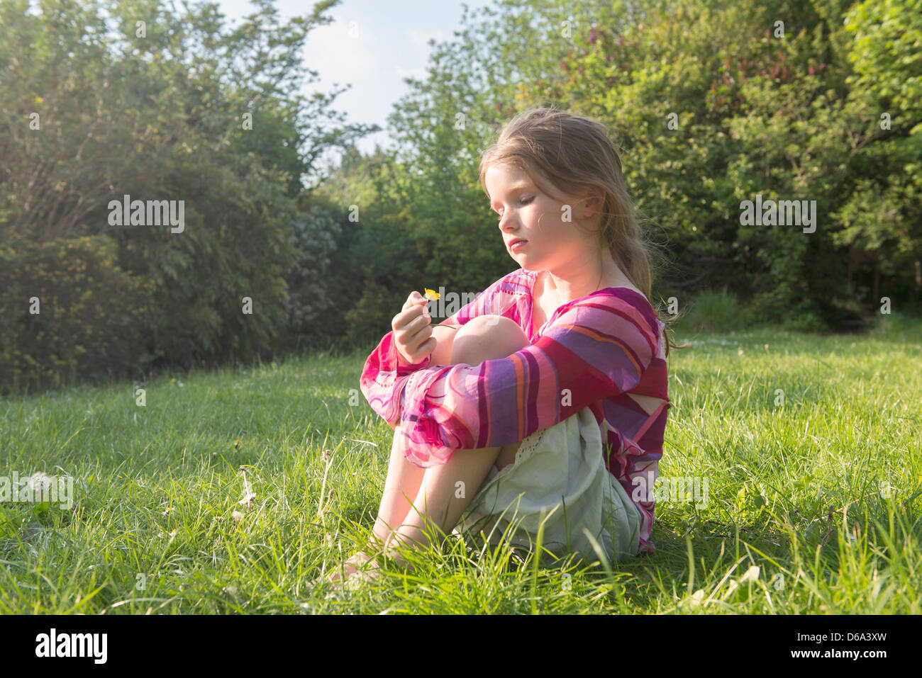 Ragazza seduta nel campo erboso Foto Stock