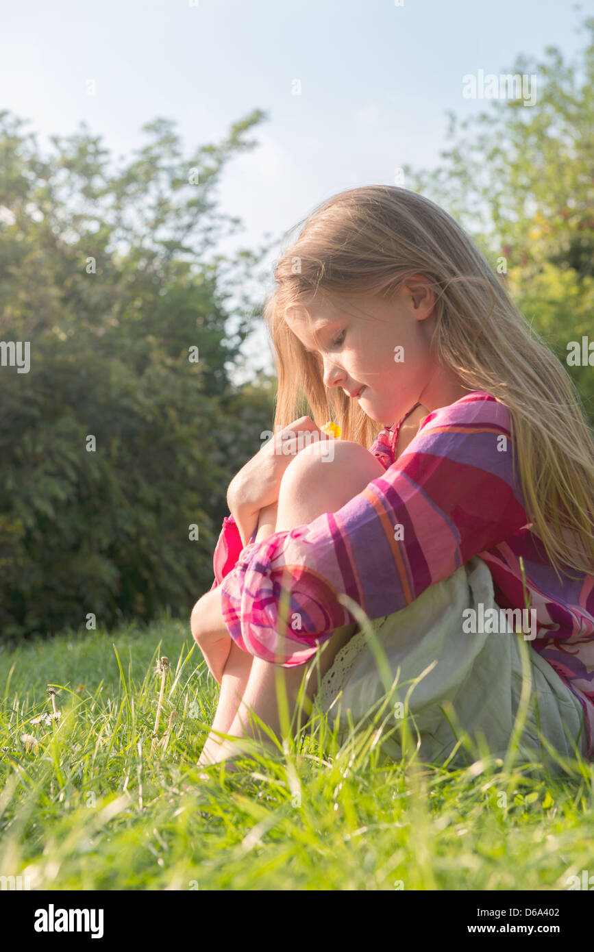 Ragazza seduta nel campo erboso Foto Stock