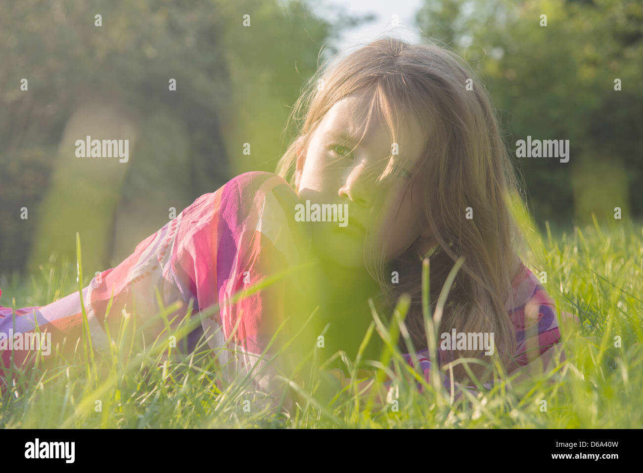 Ragazza seduta nel campo erboso Foto Stock