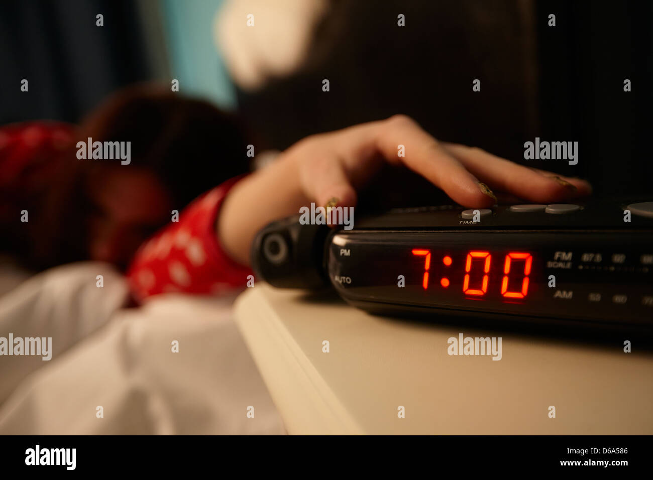 Sveglia la mattina presto con i primi anni venti donna spegnimento allarme giacente in letto in una camera da letto Foto Stock