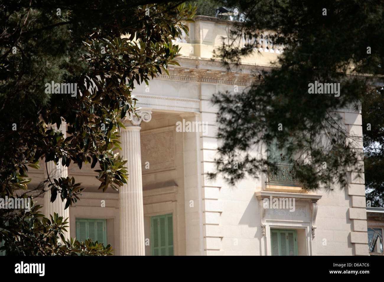 Dettaglio di una casa classica con colonne e finestra fine visto attraverso gli alberi Foto Stock