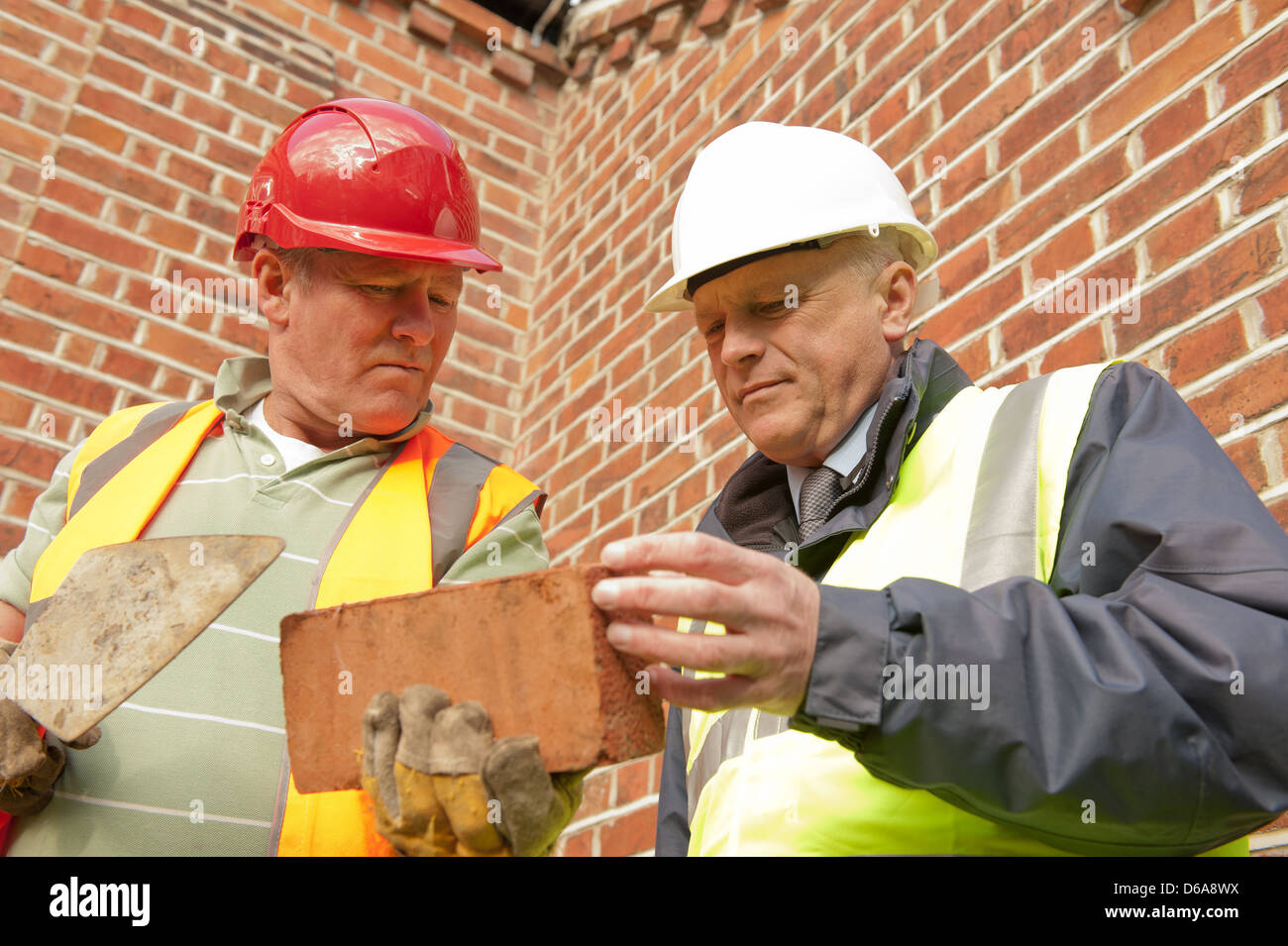 Muratore e lavora foreman/edificio inspector verifica su un mattone. Foto Stock